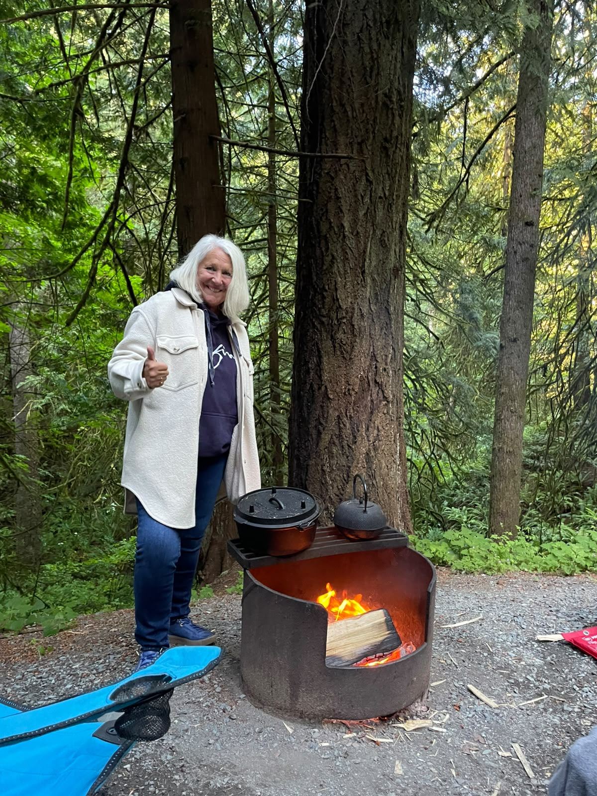 Member giving a thumbs up by the firepit with cast iron cookware