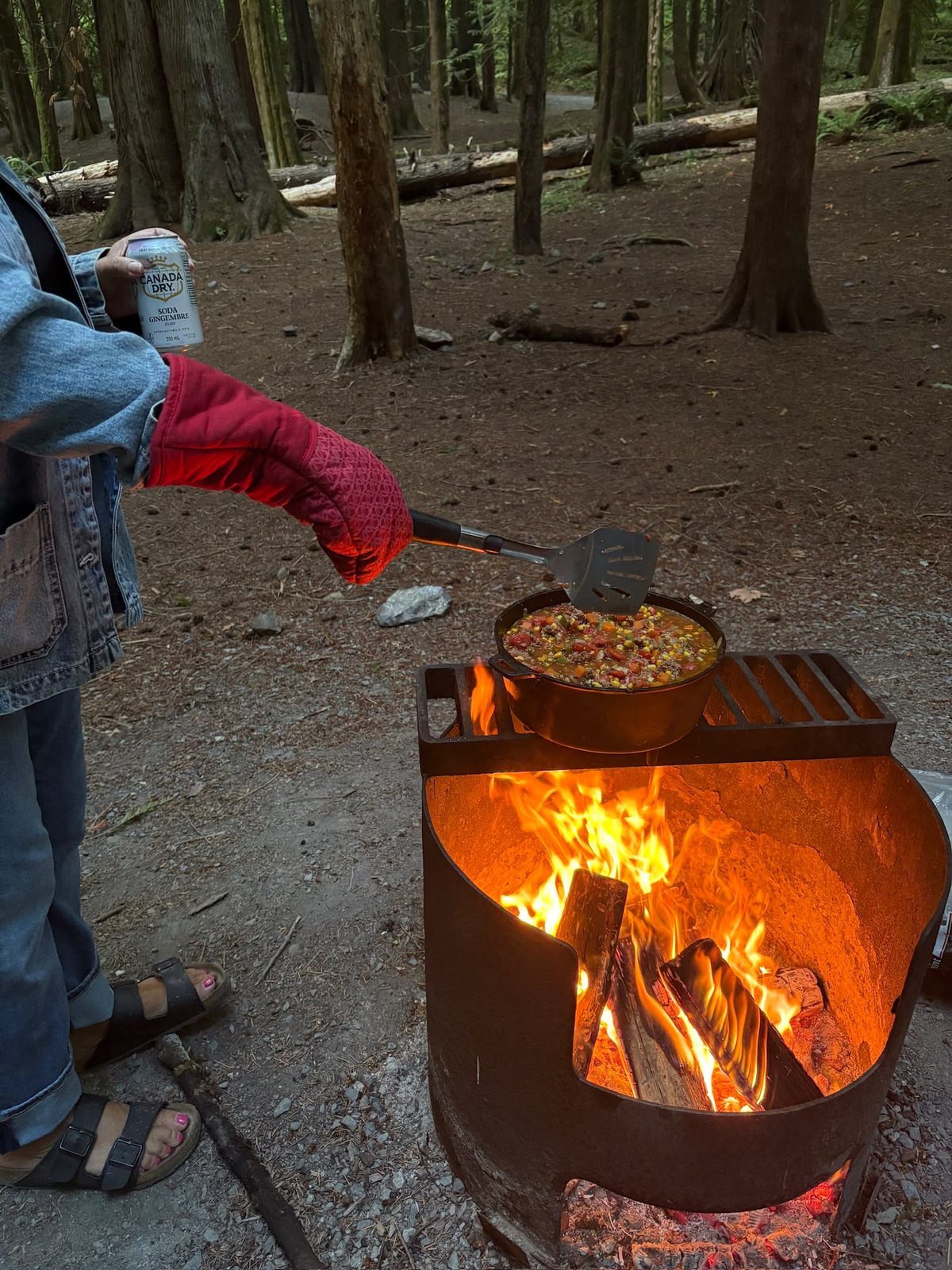 Stirring homemade chili in a cast iron Dutch oven over the campfire